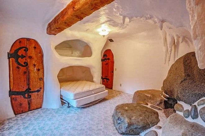 A bedroom has a mattress tucked into a cave-like nook.