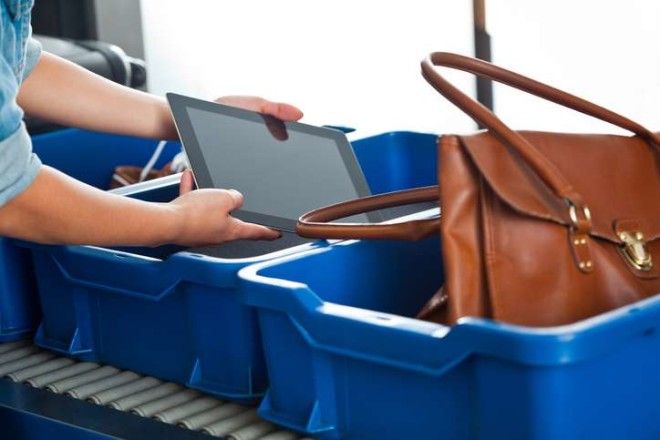 woman putting an ipad into a bin at airport security