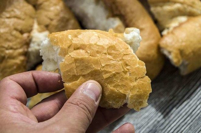 A hand holds up a piece of bread.