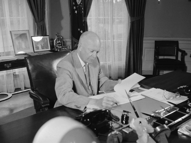 In this similar shot, Kennedy's predecessor, Dwight D. Eisenhower, works on a desk featuring a phone, ink, and lots of documents.