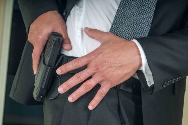 An armed bodyguard pulls a gun out of a holster