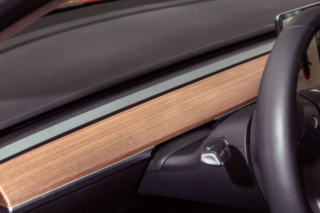 The open-grain wood and brushed metallic trim is the only real deviation from the black interior color.