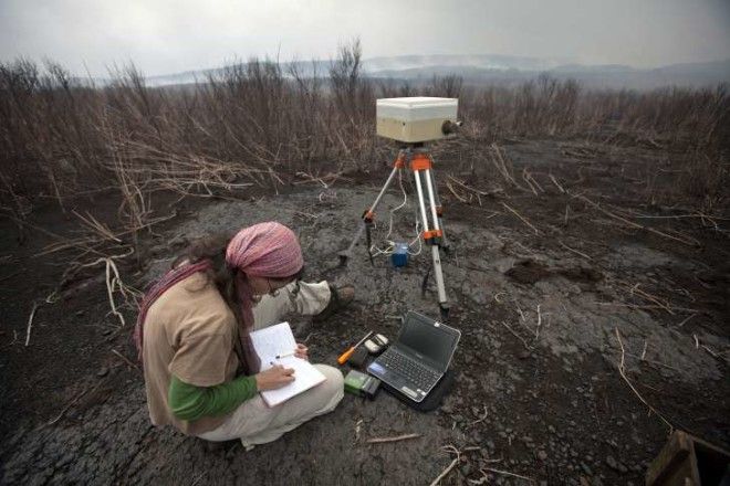 A volcanologist takes gas emission measurements during an assessment mission inside the crater at Mount Nyamulagira