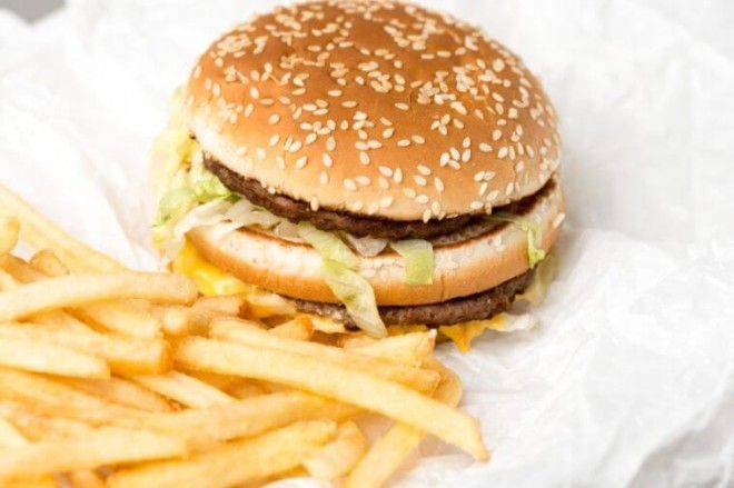 Double burger with french fries on white paper