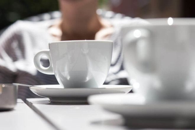 detail shot of white coffee cups on a grey wooden table outdoors